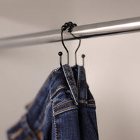Jeans hanging from a jeans hook on the closet rail