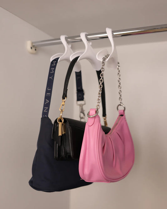 Three handbags on purse hangers in a closet