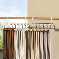 Two pants hangers full of brown and cream trousers in a closet